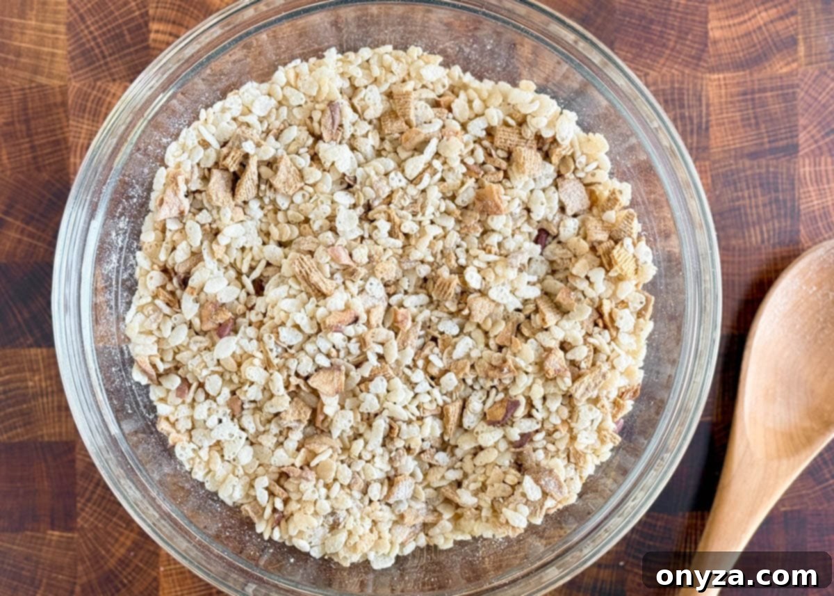 rice krispies cereal mixed with chopped dried apples, granola, and golden grahams cereal in a large bowl.