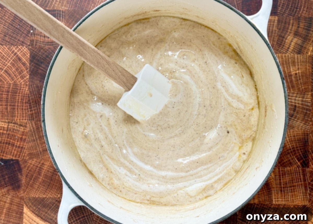 melted marshmallows in a white enameled cast iron pot with a wood handled white rubber spatula