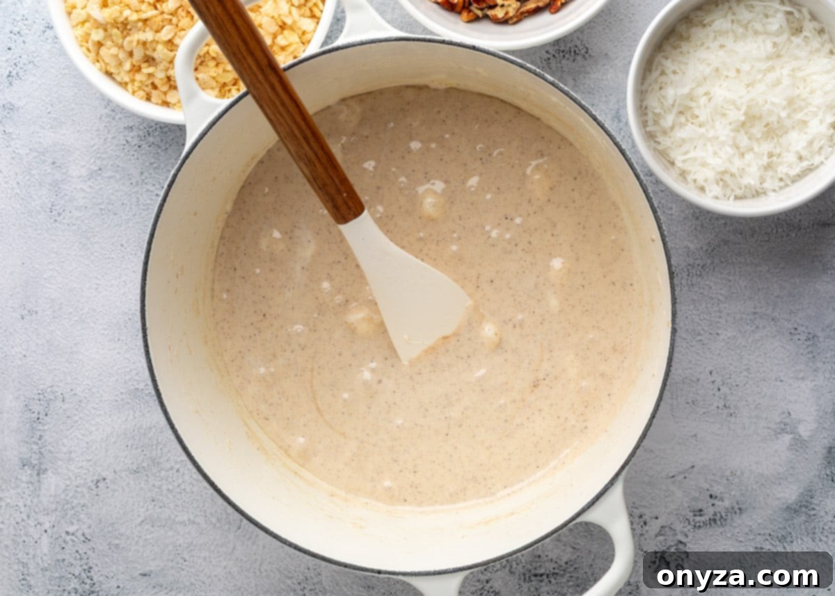 overhead of melted marshmallows in a white enameled cast iron pot with a wood handled spatula
