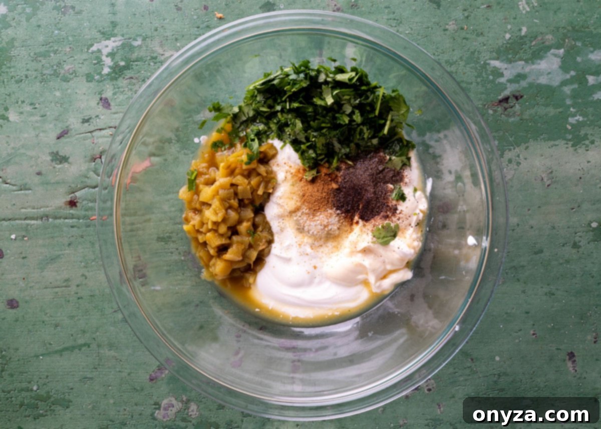 Southwestern Green Chile Cilantro Dip 4 overhead of unmixed green chile cilantro dip in a glass bowl on a green surface