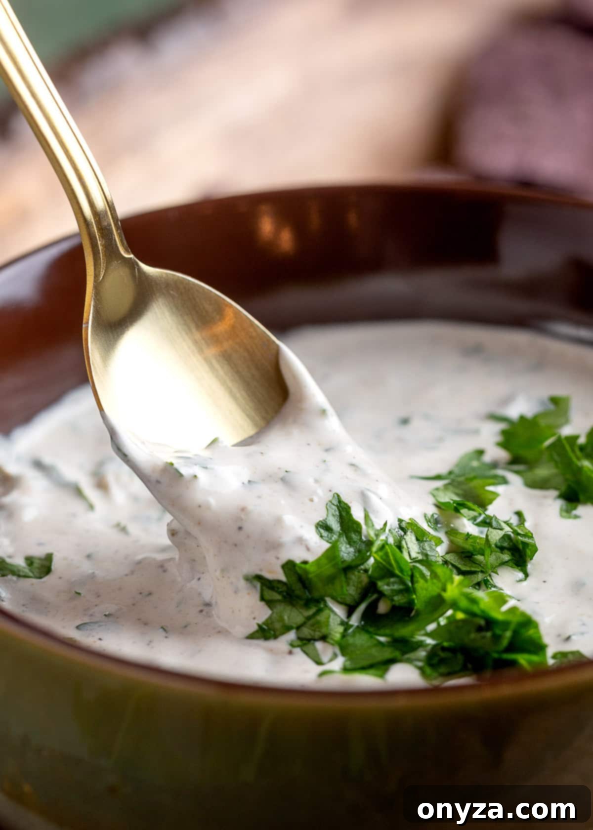 Southwestern Green Chile Cilantro Dip 6 green chile cilantro dip in a brown bowl being scooped with a gold spoon