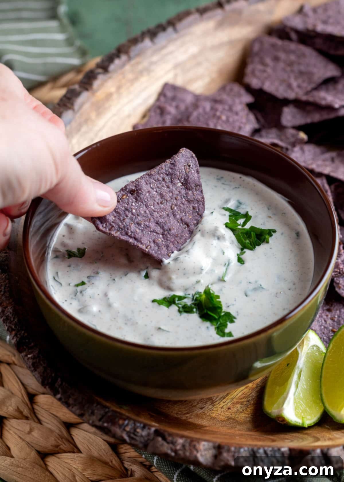Southwestern Green Chile Cilantro Dip 7 a blue corn tortilla chip being dipped into a bowl of green chile cilantro dip