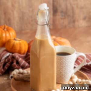 Homemade Pumpkin Spice Coffee Syrup 8 Glass swing-top bottle filled with creamy pumpkin spice coffee syrup on a wooden tray, next to a patterned white mug of black coffee. Decorative pumpkins, a striped napkin, and a wood bead garland add a fall-inspired touch.