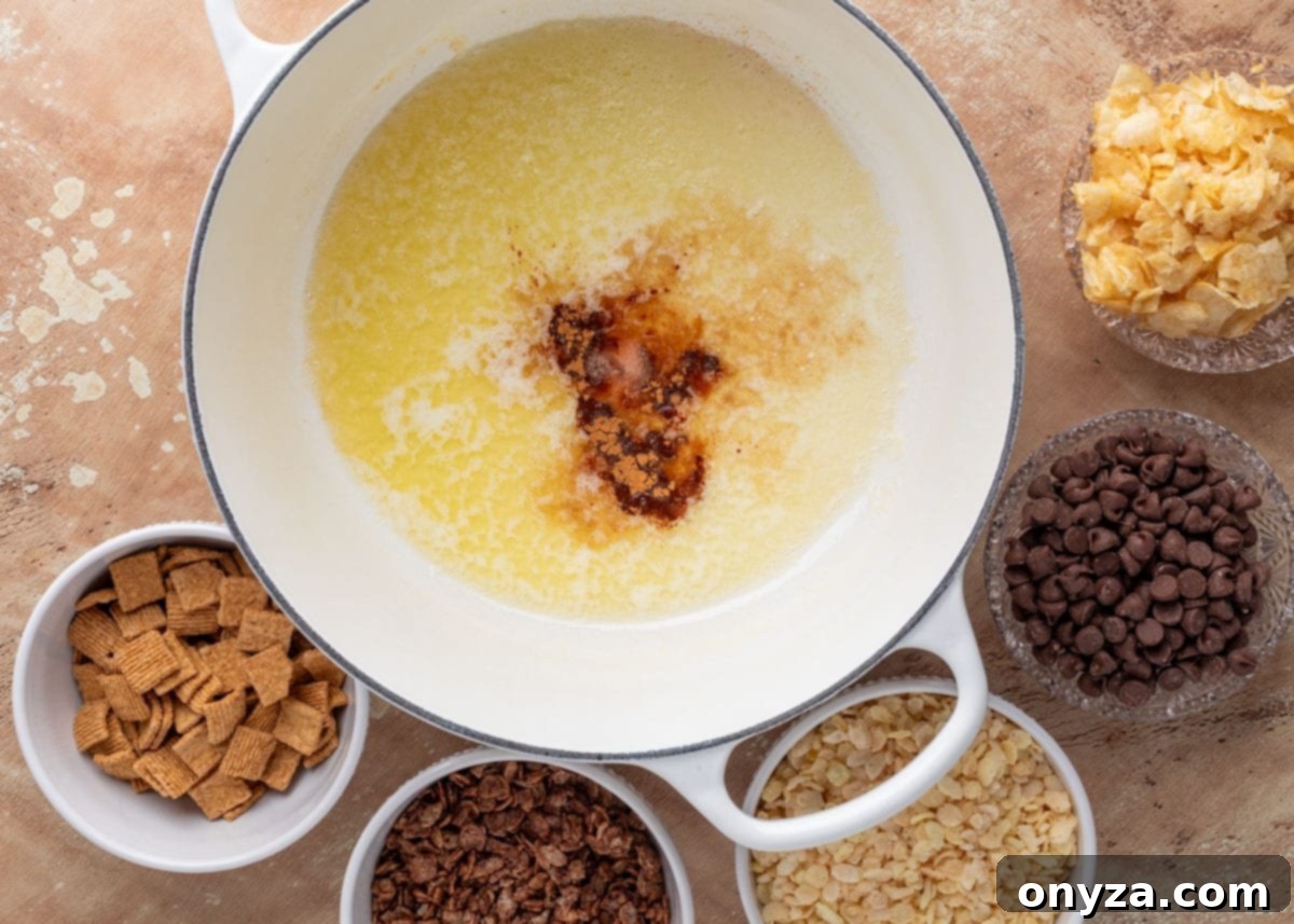 Overhead view of a white Dutch oven filled with melted butter, vanilla extract, and ground cinnamon. Surrounding the pot are small bowls of mix-ins, including chocolate chips, crushed potato chips, chocolate puffed rice cereal, cinnamon toast cereal, and crisped rice cereal.