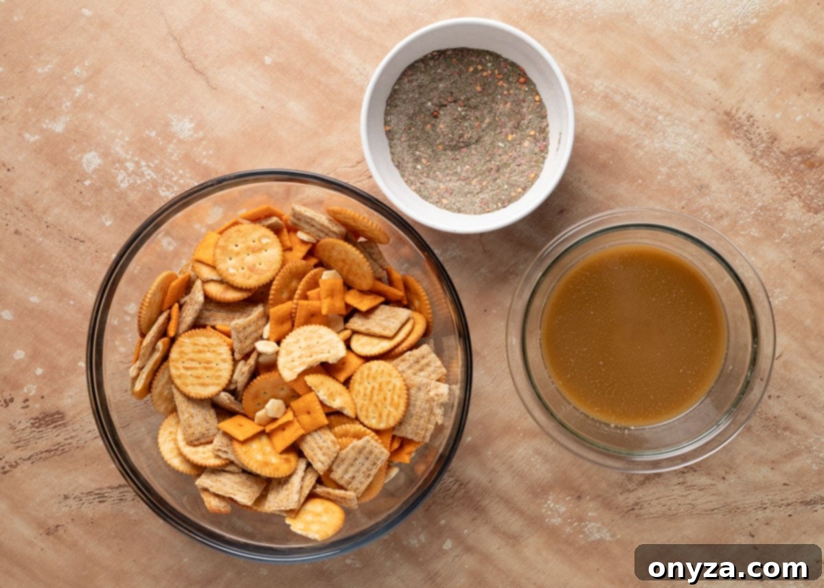 Zesty Dill Ranch Crackers 4 Overhead view of a glass mixing bowl filled with butter, cheese, and wheat crackers, next to a small white bowl of ranch seasoning mix and a bowl of melted butter and oil mixture, all on a tan surface.
