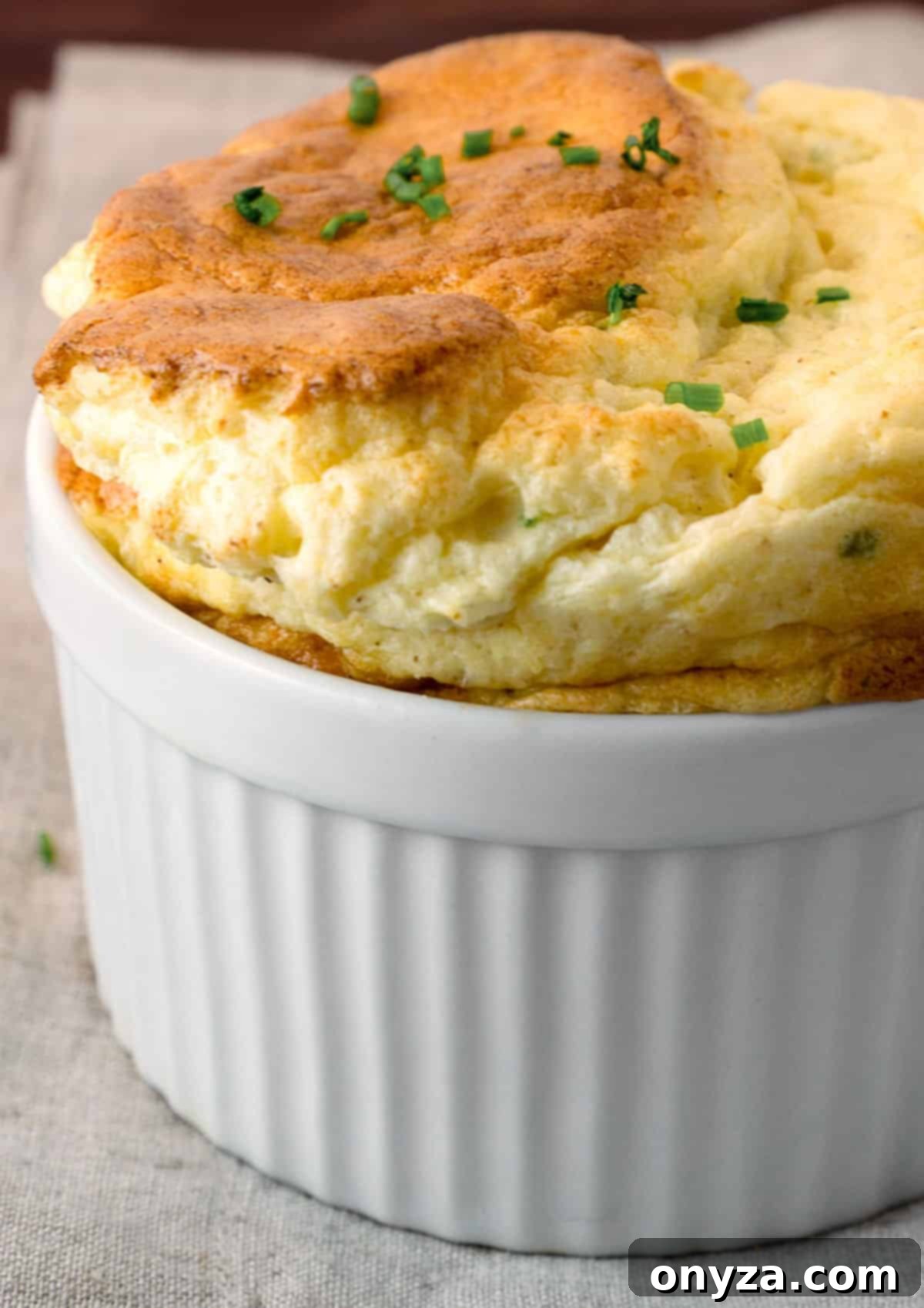 Delicate roasted cauliflower soufflé in a white ramekin, resting on a soft beige linen napkin, ready to be served.