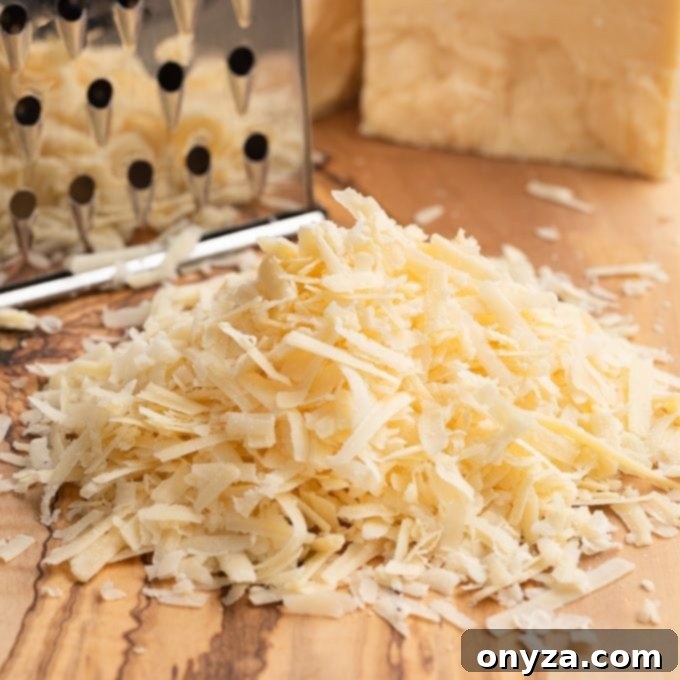 Shredded Irish Dubliner cheese on a wooden board next to a cheese grater