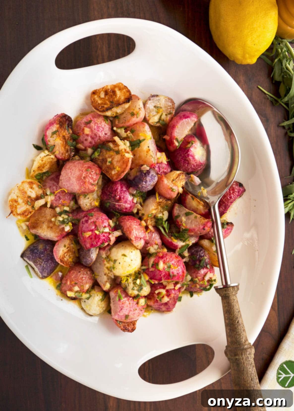 overhead photo of roasted radishes in a white serving bowl with a wood handled spoon