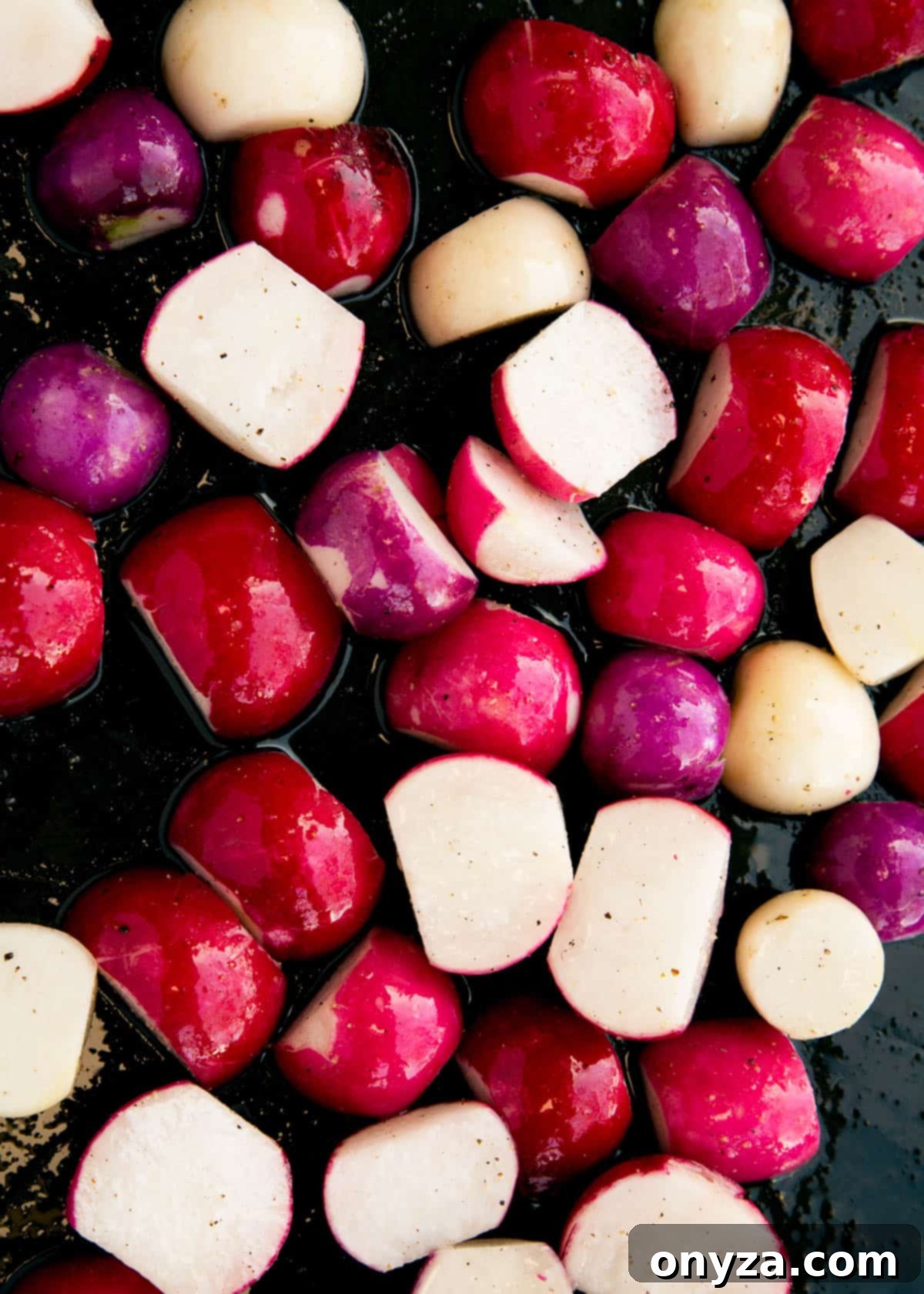 raw radishes tossed with olive oil, salt, and pepper on a baking sheet