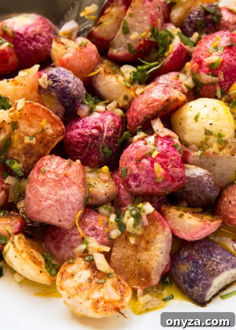 closeup of roasted radishes on a white serving platter drizzled with tarragon vinaigrette