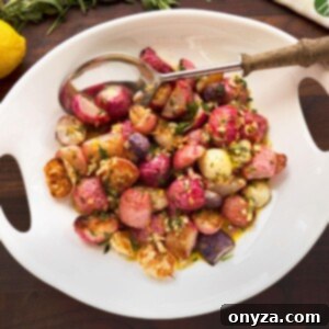 overhead photo of roasted radishes in a white serving bowl with a wood handled spoon