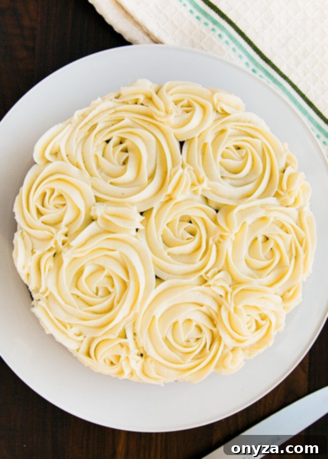 Overhead shot of a beautifully decorated carrot cake with cream cheese frosting rosettes on a white plate, highlighting the orange curd filling.