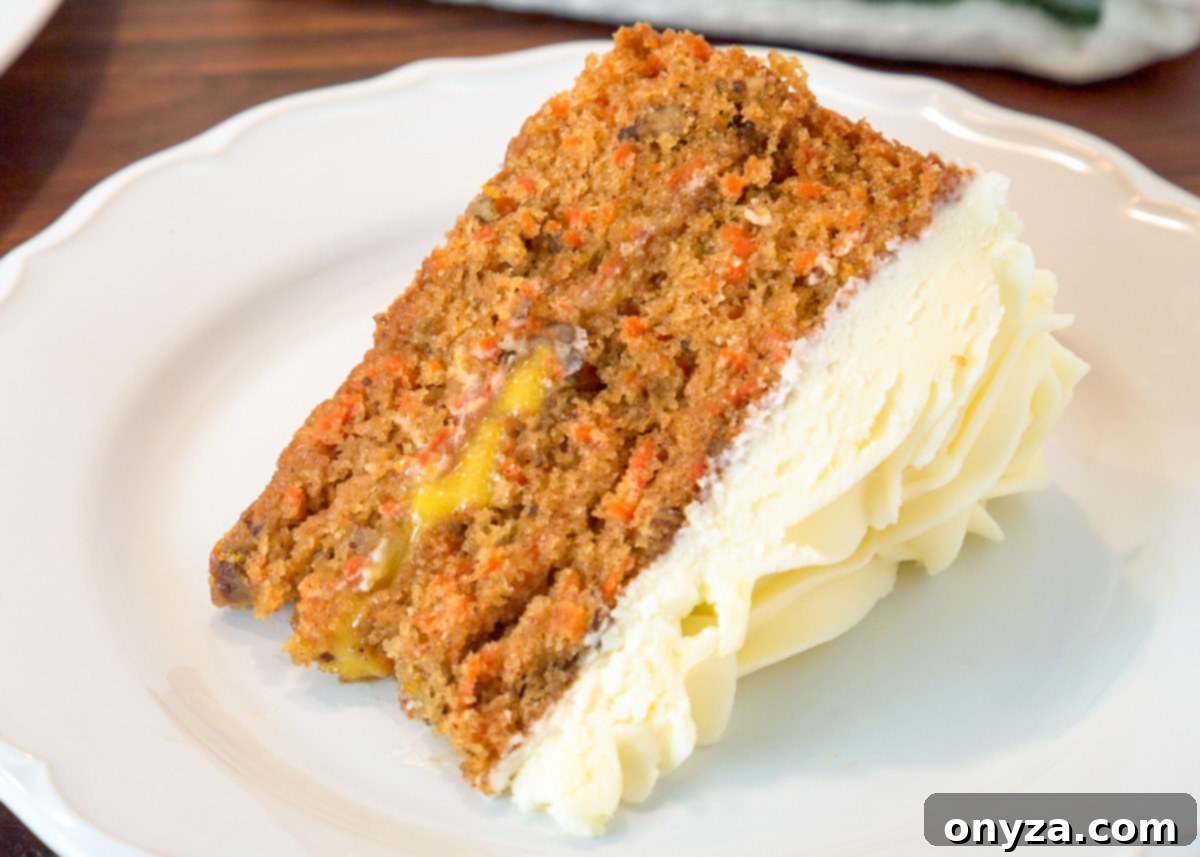 A perfectly cut slice of orange curd-filled carrot cake, showcasing the distinct layers of cake, curd, and cream cheese frosting, on a white plate.