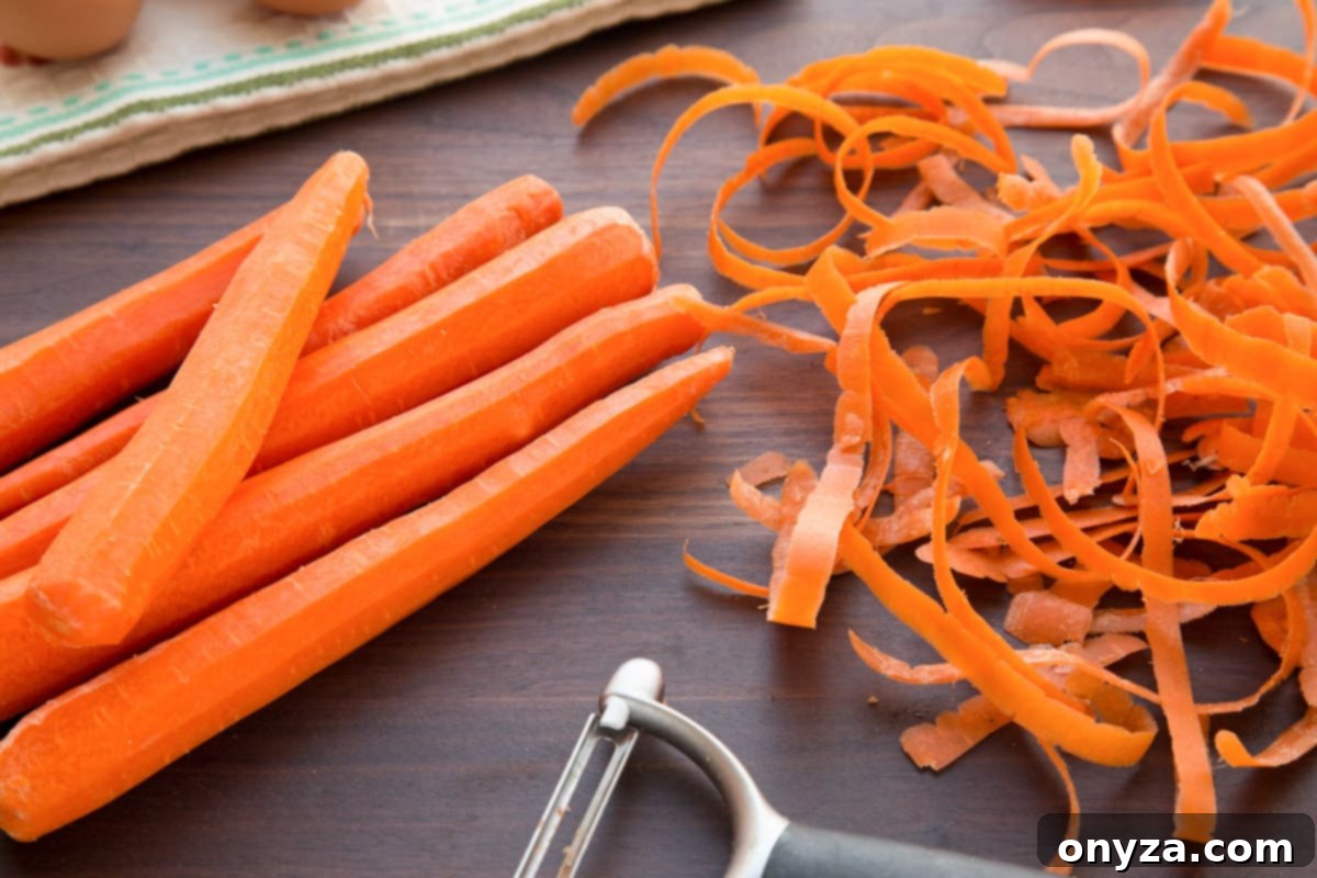 Fresh, whole carrots and peels on a dark wooden cutting board, ready for shredding, emphasizing the natural ingredients.