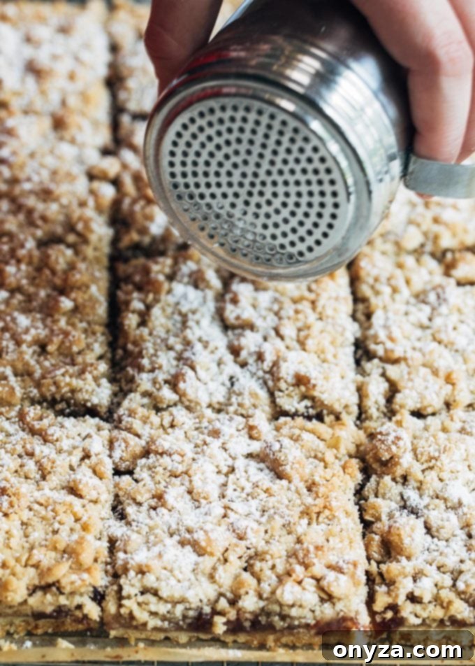 Dusting baked jam bars with powdered sugar on a cutting board