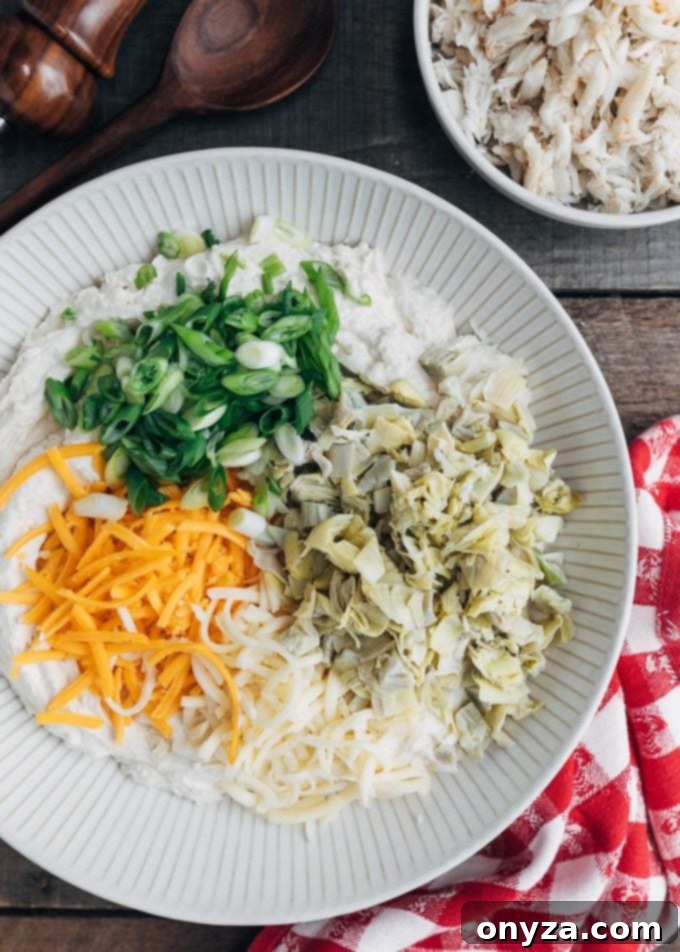 Cheddar and Monterey Jack cheeses, artichoke hearts, and scallions in bowls, ready for the crab dip