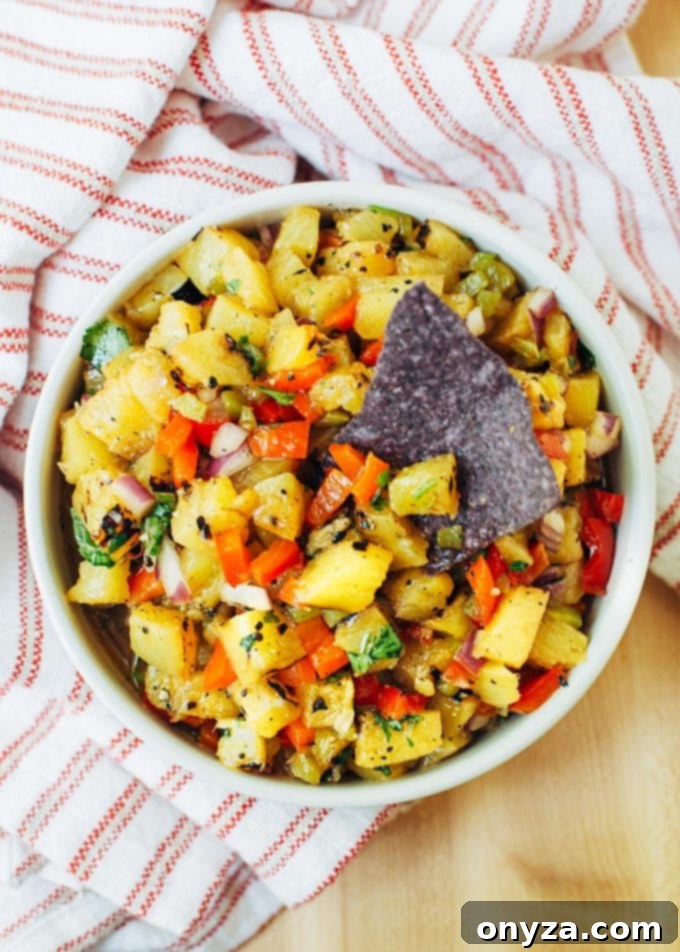 Sweet & Smoky Grilled Pineapple Salsa 6 Close-up of vibrant pineapple salsa in a bowl, accompanied by a blue corn chip