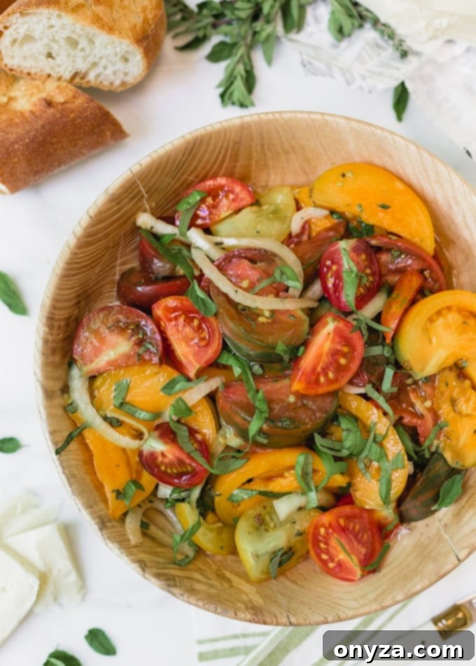 Heirloom tomato salad with onions and basil in a wooden bowl