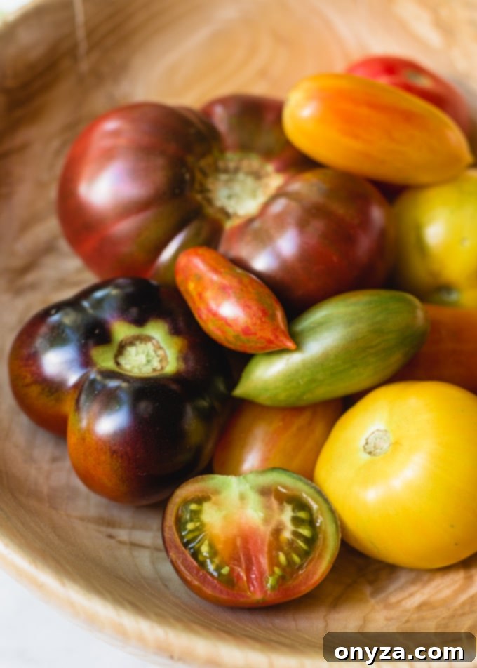 Assorted heirloom tomatoes in a hand-carved wooden bowl, showcasing their variety