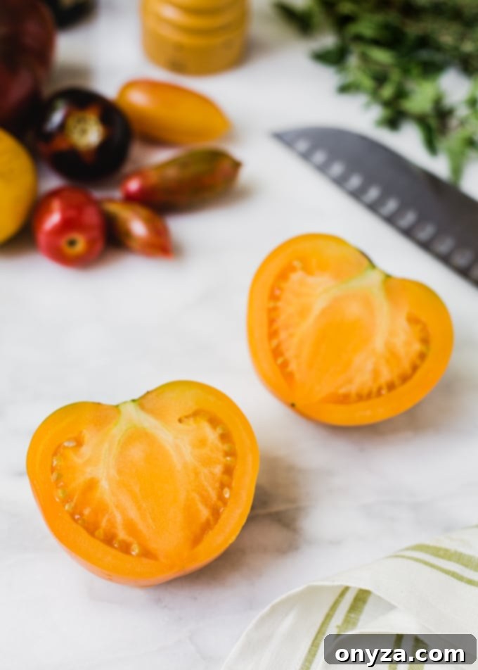 Halved orange tomato on a marble board with a santoku knife, ready for slicing