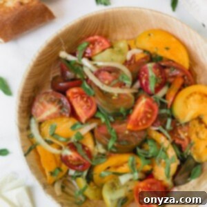 Heirloom tomato salad with onions and basil in a wooden bowl