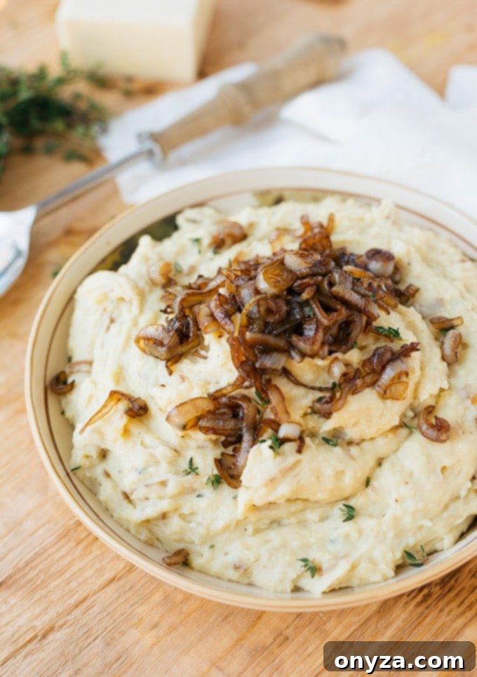 Creamy Caramelized Shallot and Cheddar Mashed Potatoes served in a bowl, garnished with fresh thyme and extra shallots, perfect for a holiday feast.