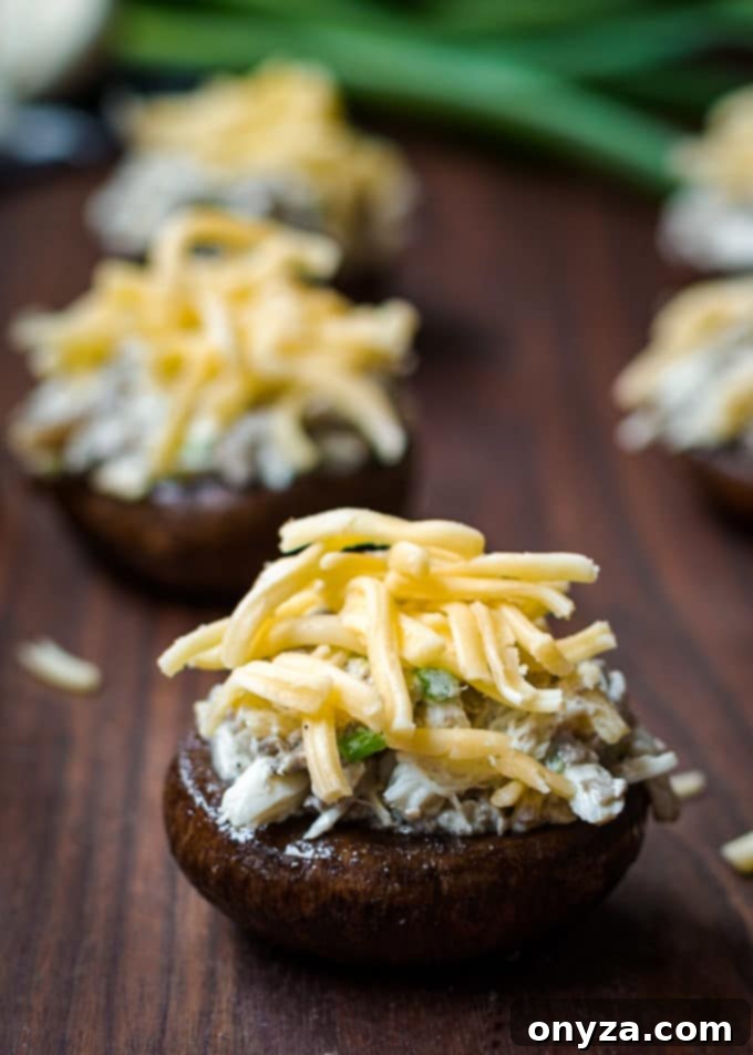 Unbaked Gouda and crab stuffed mushrooms arranged neatly on a wood cutting board, ready for the oven.