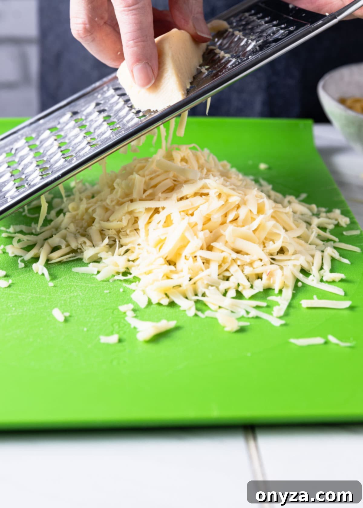 grating fontina cheese on a green cutting board