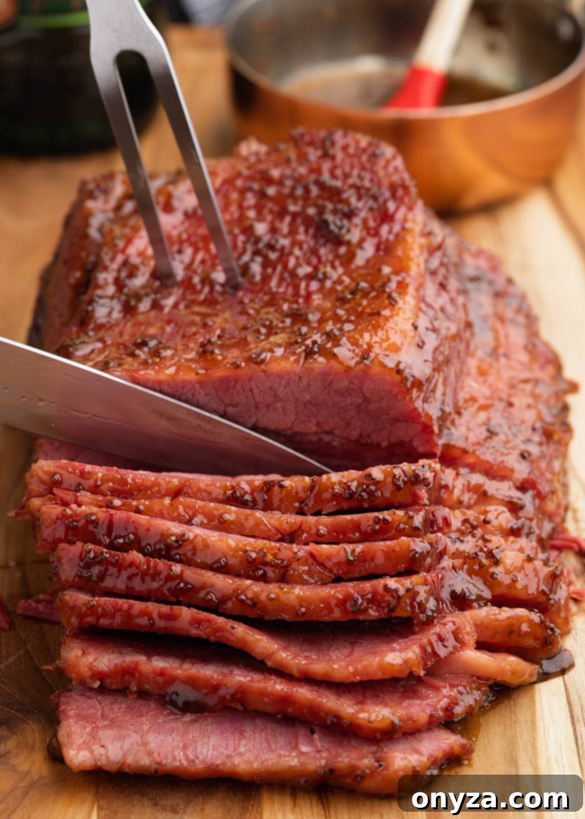 Golden Beer Braised Corned Beef Glazed with Whiskey Mustard 8 Glazed corned beef on a wood cutting board being sliced with a knife and meat fork