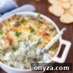 A serving spoon digging into hot spinach and artichoke dip, served in a small bowl