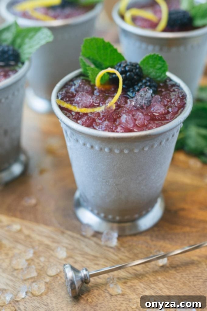 an icy Blackberry-Lemon Mint Julep served in a beaded julep cup, with mint garnish and berries