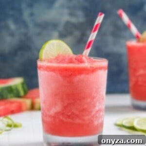 A frosty glass of Frozen Watermelon Daiquiri with a lime wedge garnish, captured close-up to show its smooth texture.