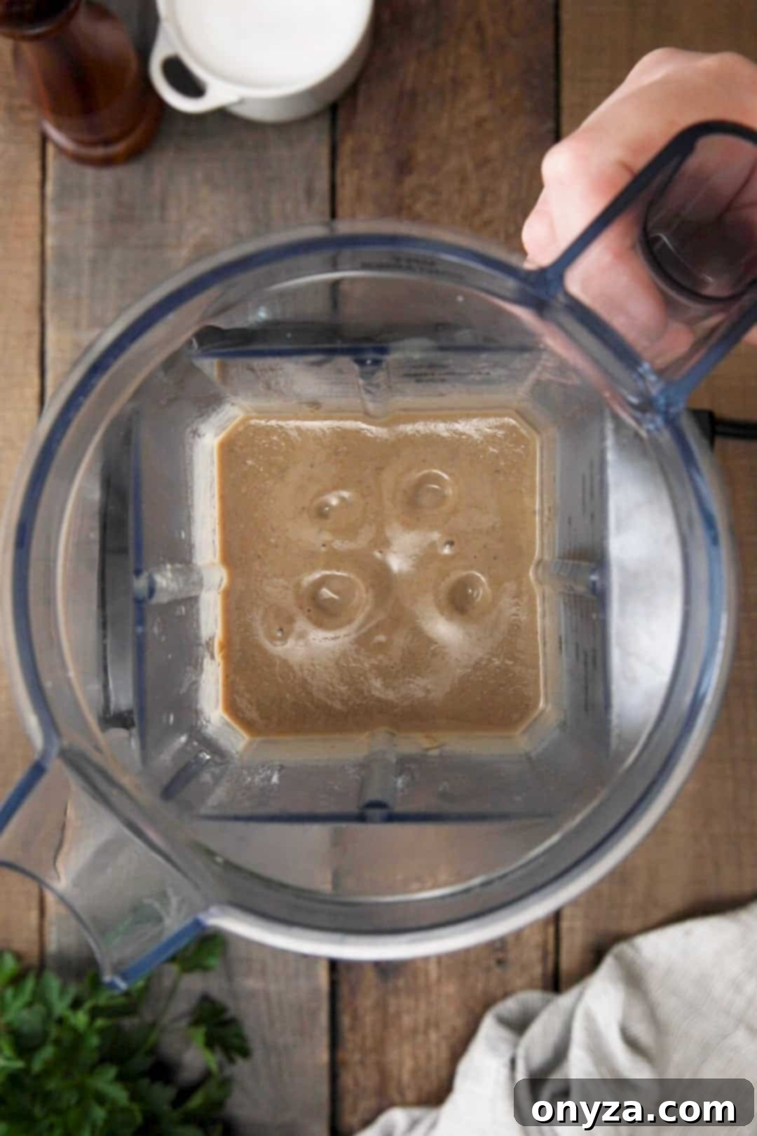 Overhead view of pureed mushroom soup in a blender canister, showing a smooth, creamy texture.