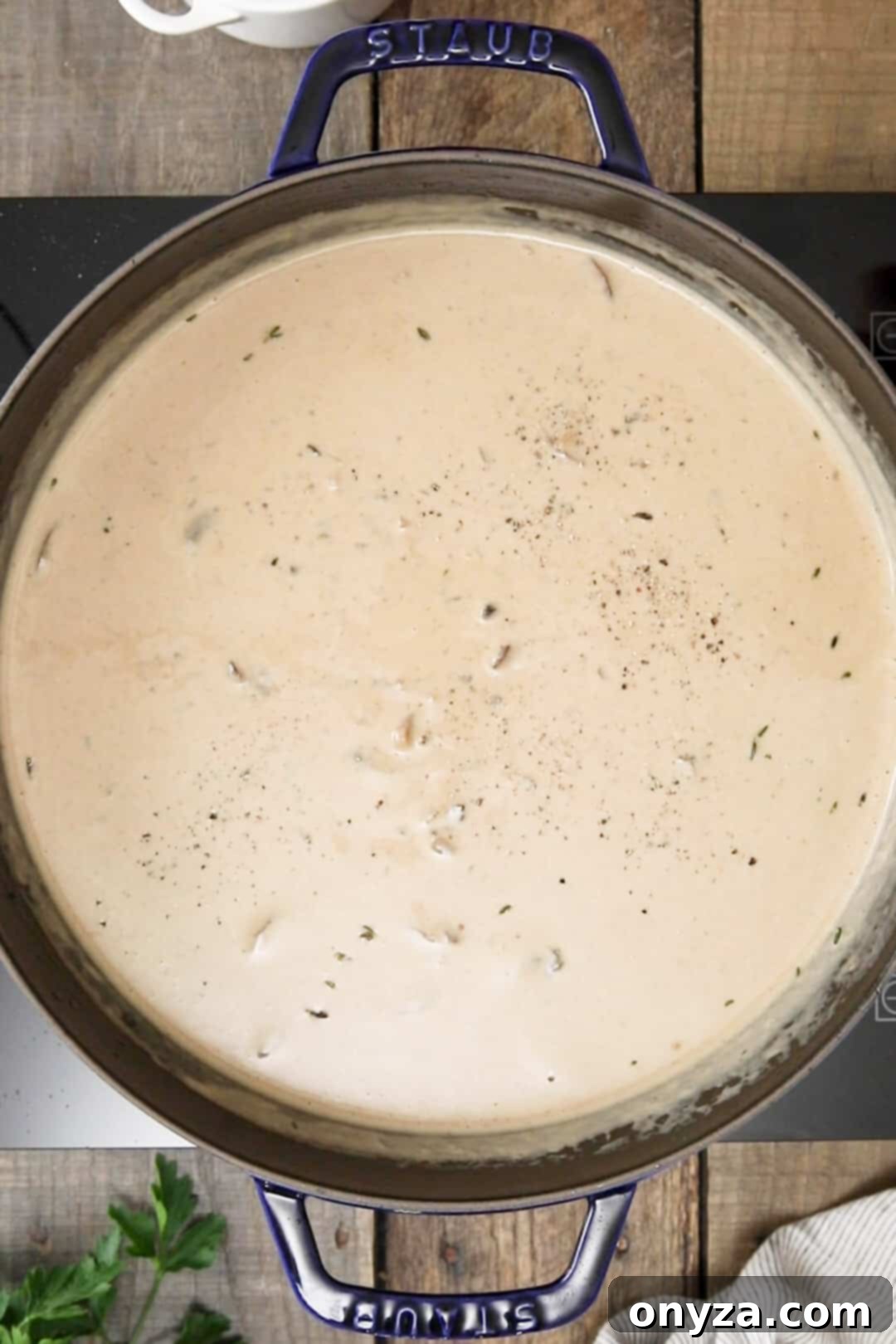 Overhead view of the finished creamy mushroom soup in a black enameled cast iron Dutch oven, ready to be served.