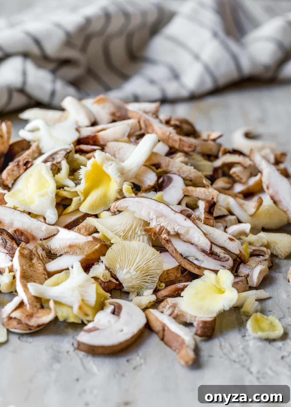 A vibrant pile of freshly sliced cremini, shiitake, and chanterelle mushrooms on a cutting board, ready for cooking.