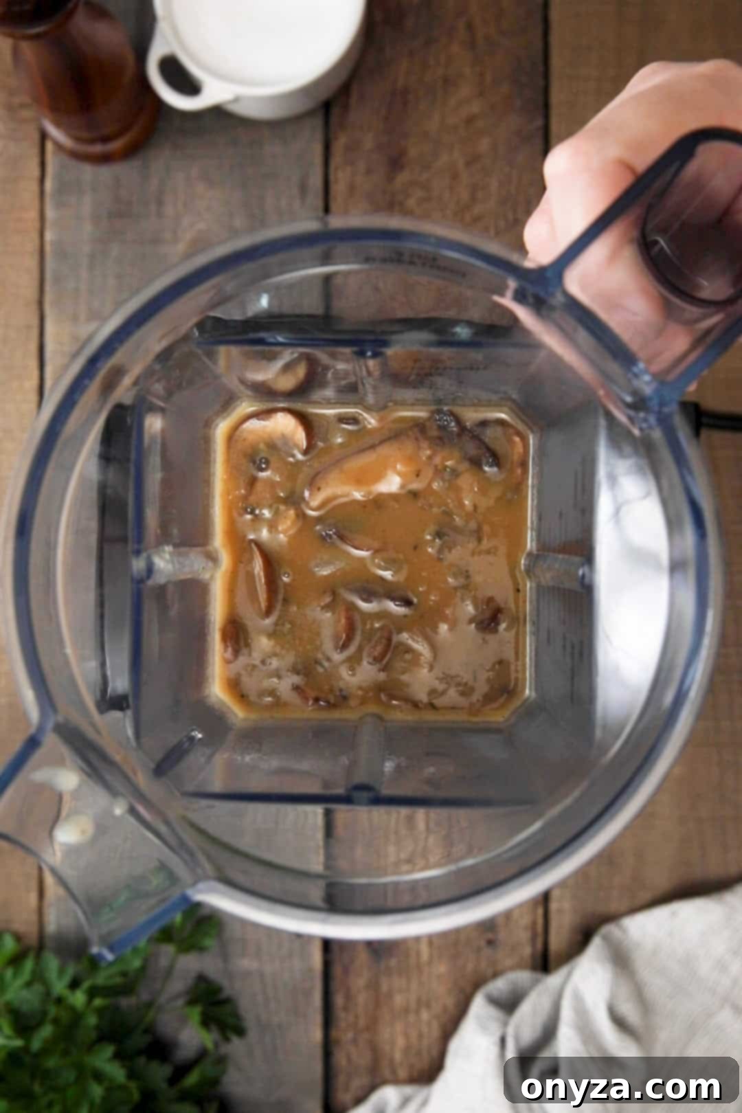Overhead view of mushroom soup in a blender canister before pureeing, showing distinct pieces.