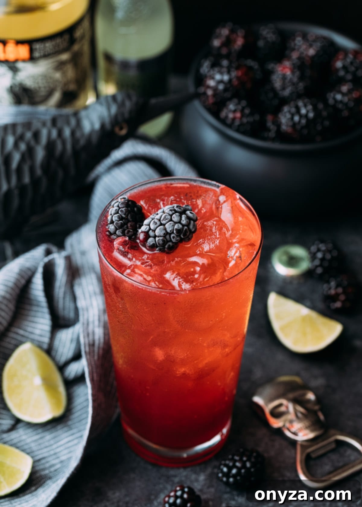 Vibrant Blackberry El Diablo cocktail in a highball glass, garnished with fresh blackberries, set against a spooky yet elegant Halloween backdrop featuring subtle cobwebs and dark, atmospheric lighting. The deep red liquid shimmers invitingly, promising a delicious taste.