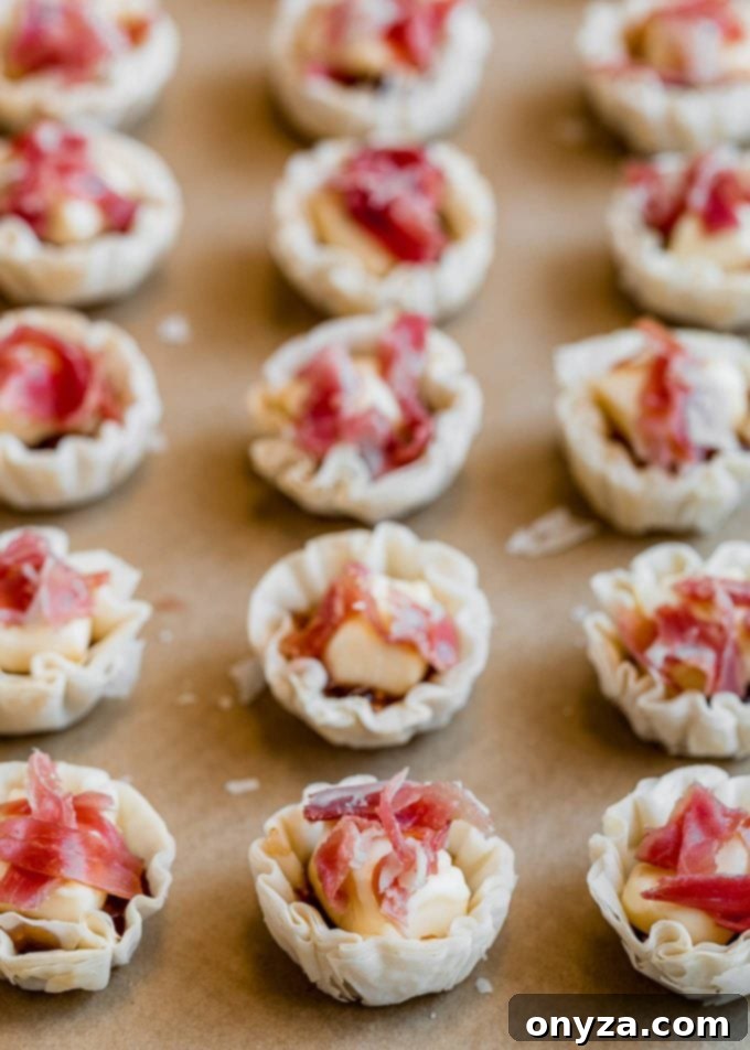 phyllo cups filled with brie and prosciutto on a baking sheet