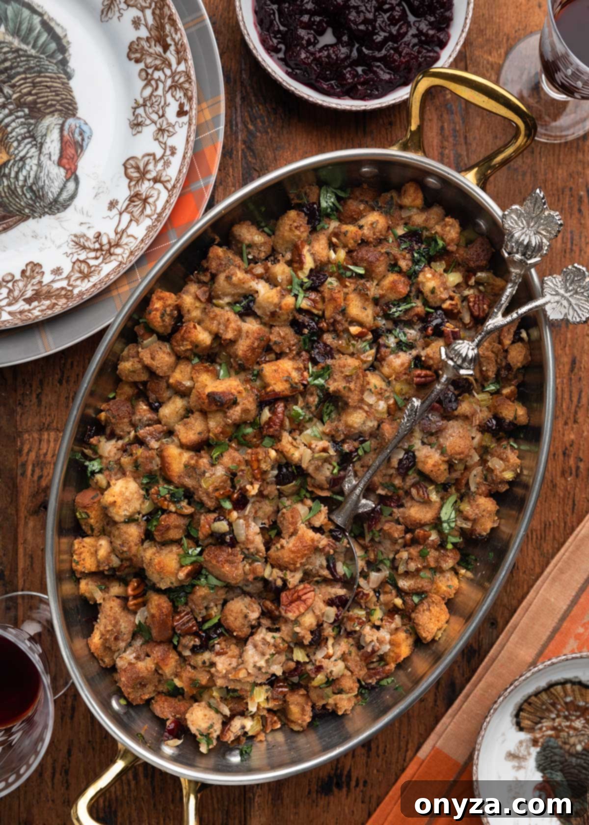 Festive Cranberry Pecan Stuffing 2 overhead photo of cranberry pecan stuffing in a copper gratin with an ornamental serving spoon