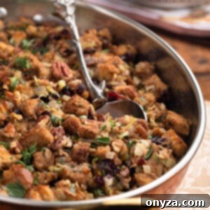 Festive Cranberry Pecan Stuffing 7 side view of baked cranberry pecan stuffing in a gratin dish with a silver serving spoon