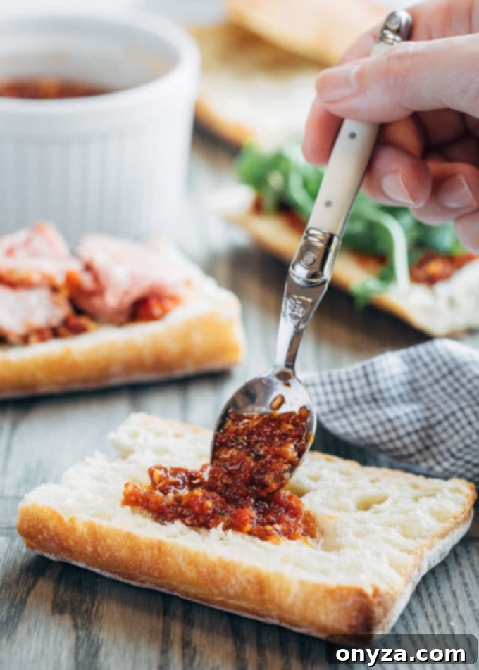Gourmet Roast Beef Sandwiches with Sun-Dried Tomato Pesto 2 Spoon applying pesto rosso onto ciabatta bread for gourmet roast beef sandwiches