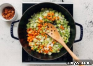 Carrots, celery, and leeks being sautéed in a Staub pot, softening and browning for the soup base.