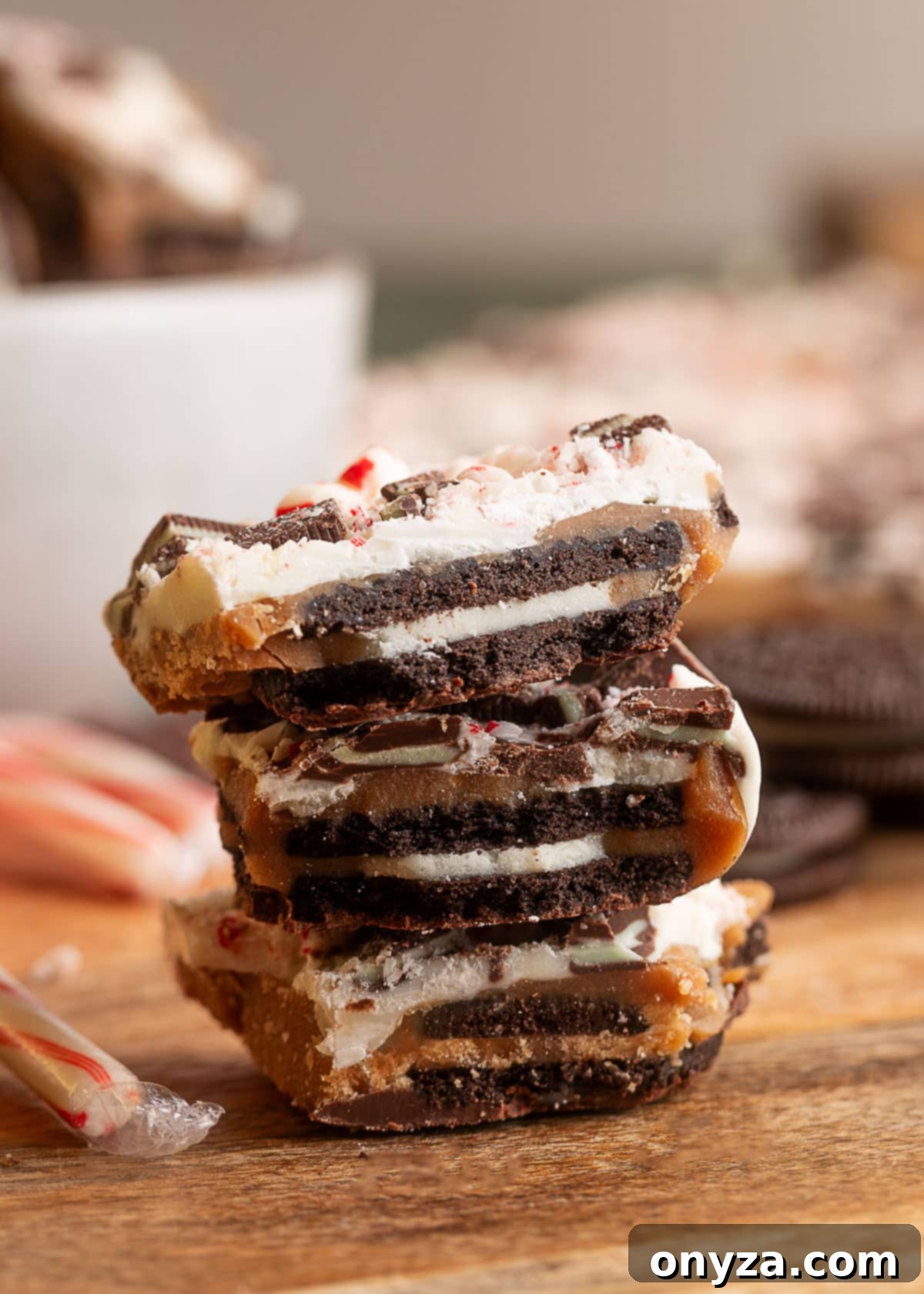 Stack of Oreo mint toffee bark pieces, showing the defined layers of chocolate cookies, toffee, white chocolate, Andes mints, and crushed peppermint.