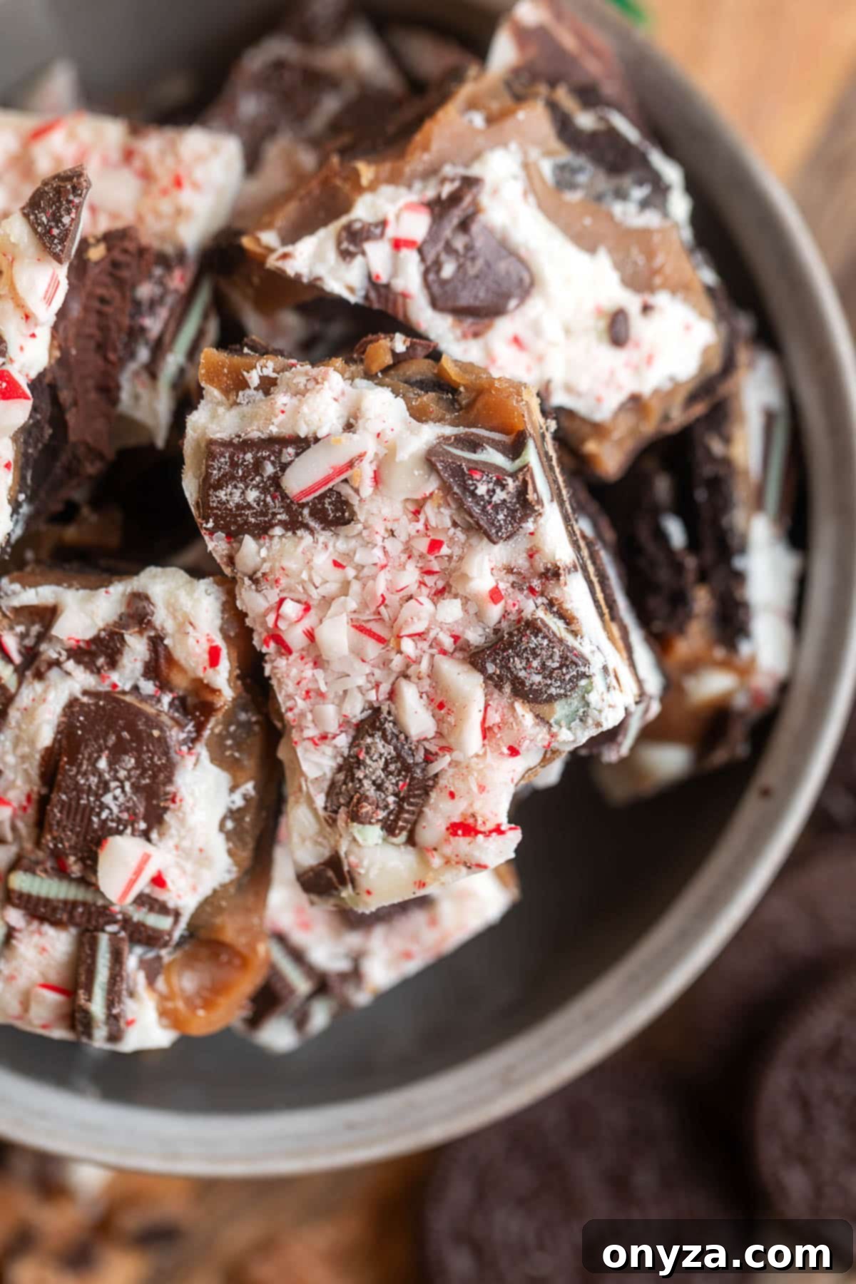 Close-up of broken pieces of Oreo mint toffee bark, showing the layers of toffee, white chocolate, chopped Andes mints, and crushed peppermint candy.