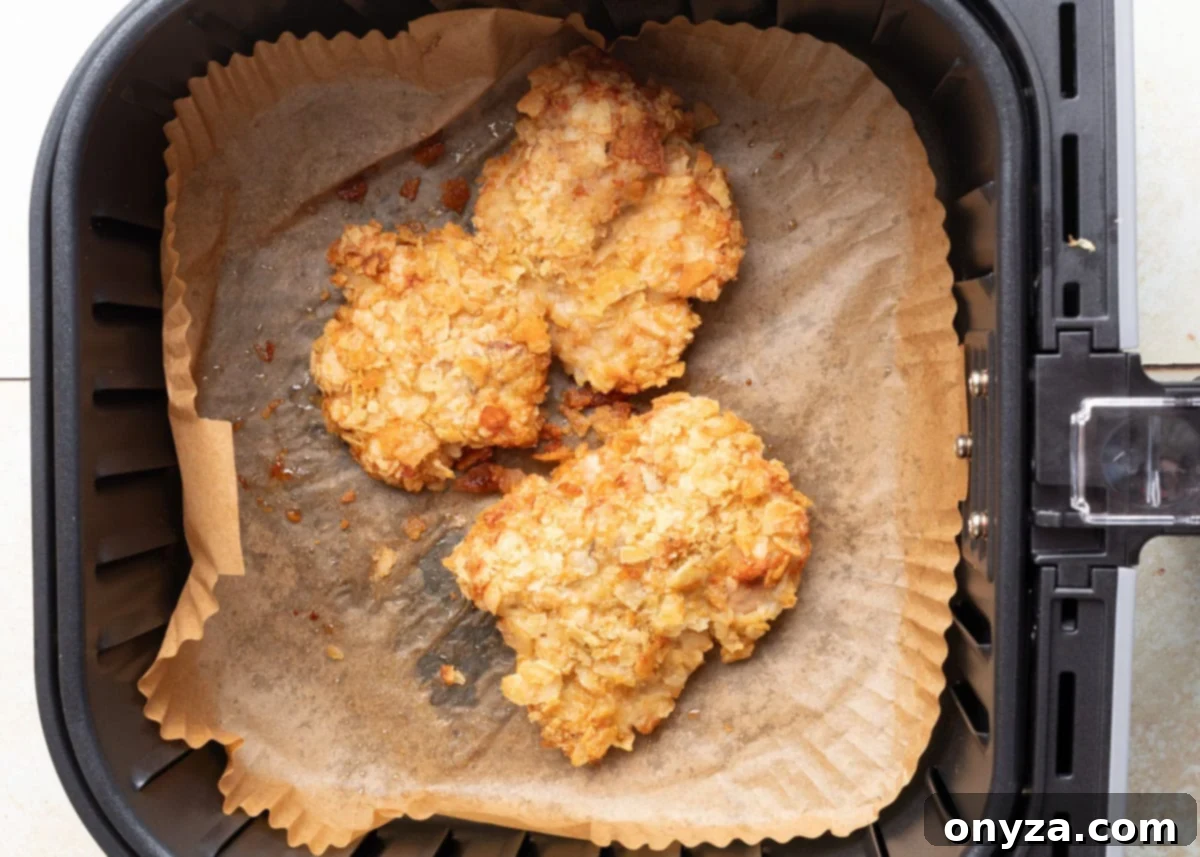 Crispy potato chip-crusted chicken thighs in an air fryer basket